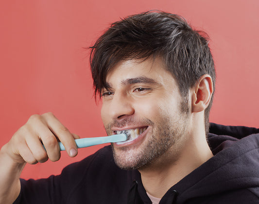 A Handsome young man holding and brushing his teeth with an electric toothbrush