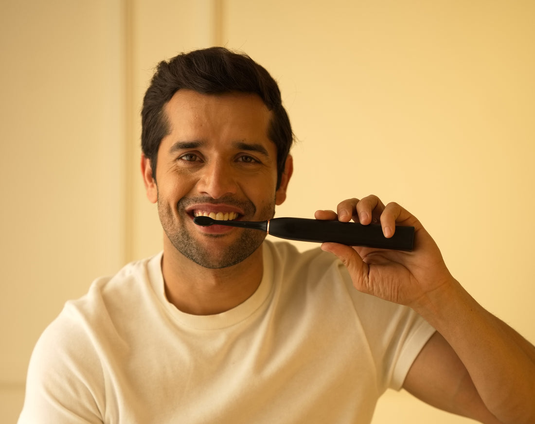 Smiling man with strong and healthy teeth, brushing using an electric toothbrush