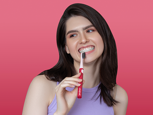 a young pretty girl using a soft bristled electric toothbrush