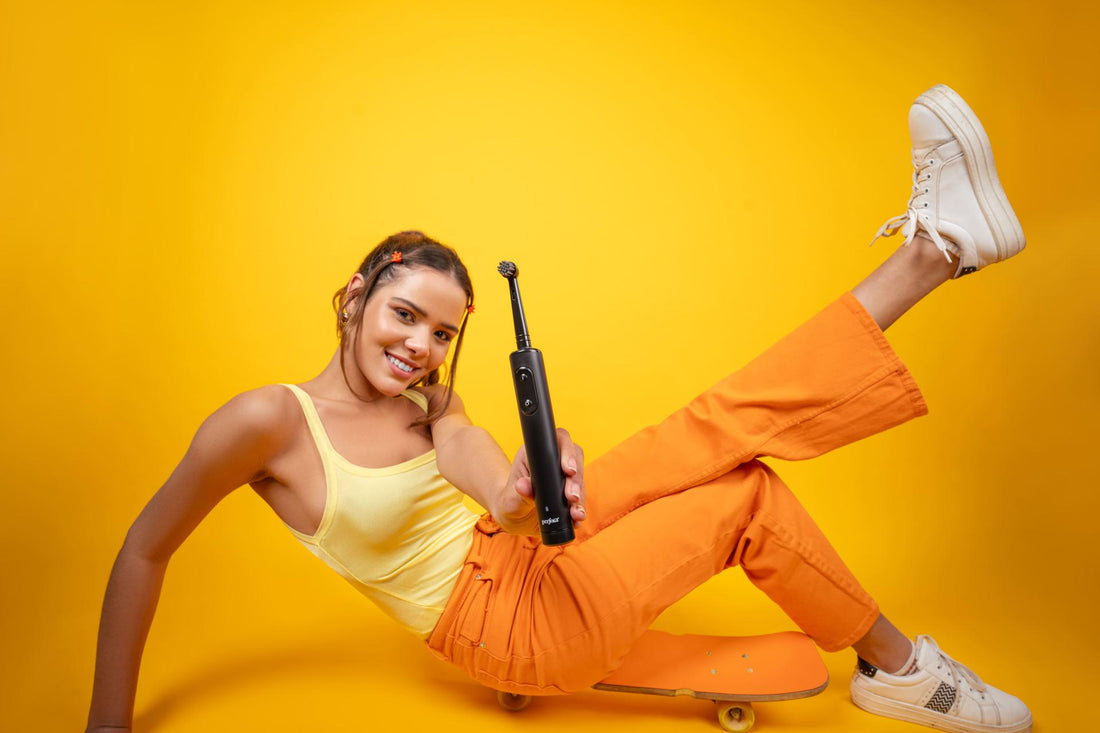 A woman in front of a yellow background, posing with Perfora's oscillating toothbrush